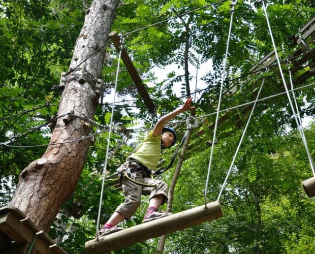 Girl on log bridge at ropes course