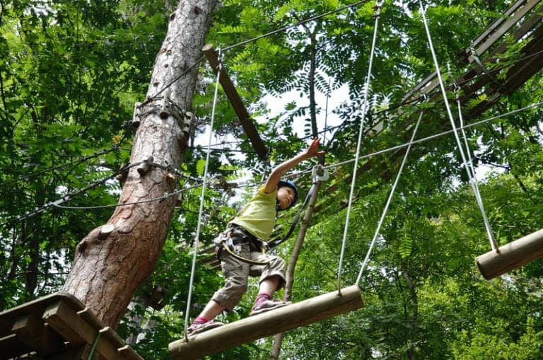 Girl on log bridge at ropes course