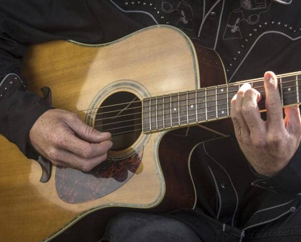 Close up of man dressed in country music clothes playing guitar