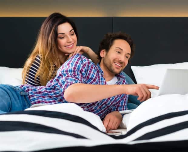 Couple using laptop with wifi in hotel room