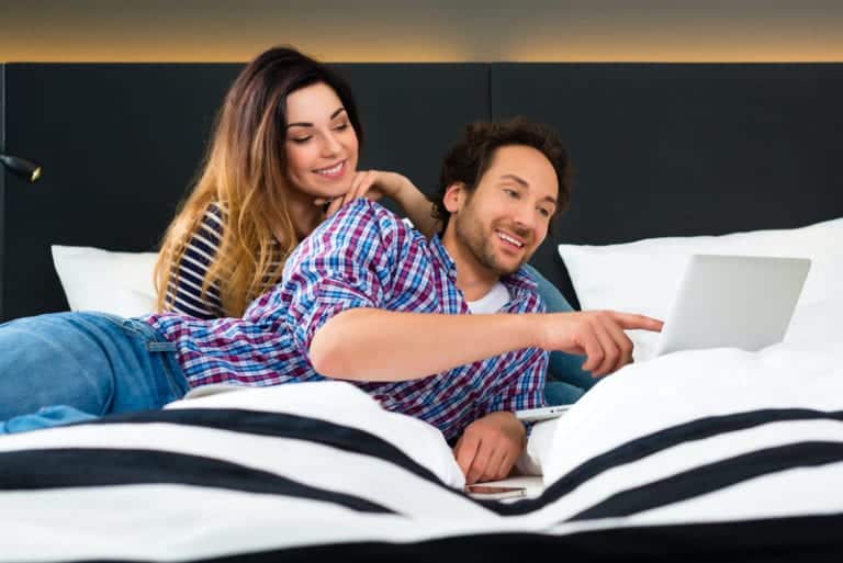 Couple using laptop with wifi in hotel room