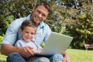 Dad and son using laptop wifi outside