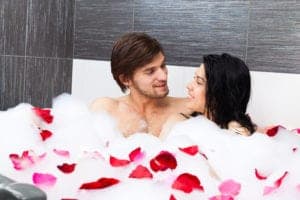 Romantic couple snuggling in the bubbly tub with rose petals at their Pigeon Forge hotel Jacuzzi suite.