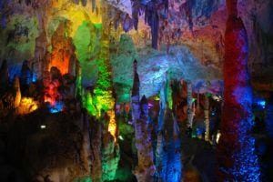 Stalactites-and-stalagmites-covered-in-colorful-lights-in-a-cave