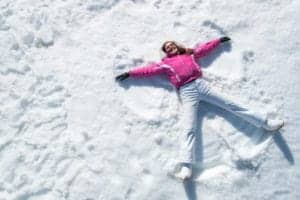 happy lady in pink jacket making snow angel